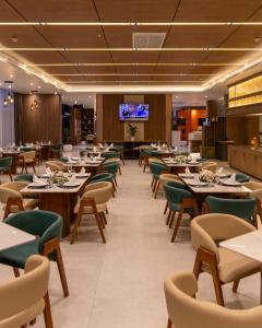a dining room with tables and chairs and a tv at Atlantis Alger Aéroport ex Ibis in Alger
