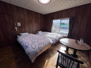 a bedroom with a bed and a table and a window at Hillshouse2はなれ in Tokoname