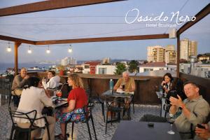 a group of people sitting at tables on a rooftop at Hotel Boutique Ossido Nero in Viña del Mar