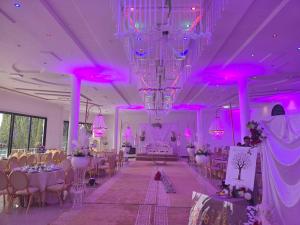 a banquet hall with purple lighting and tables and chairs at Tahla Garden in Tahla