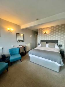 a bedroom with a large bed and a blue chair at Riverside Cottage B&B in Lynmouth