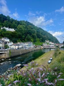 a river in a town with houses and a mountain at Riverside Cottage B&B in Lynmouth