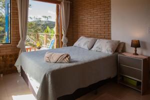 a bedroom with a large bed with a window at Casa Mohini Refúgio nas montanhas de Teresópolis Quarto com deck rede suspensa, lareira e cachoeira in Teresópolis