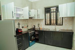 a kitchen with black cabinets and white appliances at Kigali Great Garden in Kigali