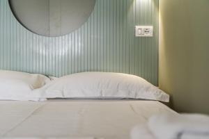 a bed with white pillows and a green wall at Amel's Rooms by PikHost in Tirana