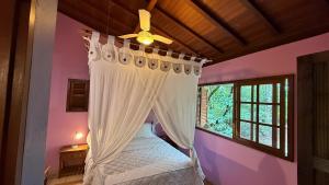 a bedroom with a canopy bed with a window at Pousada Taman Baru in Pirenópolis +64 photos