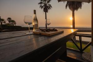 a bottle of wine and two glasses on a table with the ocean at Beachfront Bliss in Langstrand