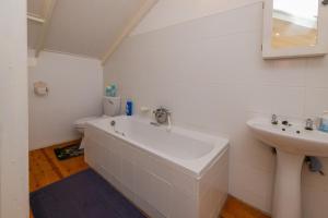 a bathroom with a tub and a sink and a toilet at Beachfront Bliss in Langstrand