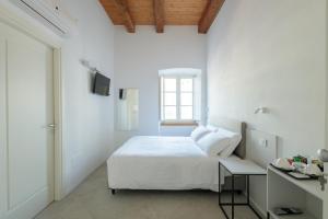 a white bedroom with a bed and a window at Palazzo Simonetti in Ascoli Piceno