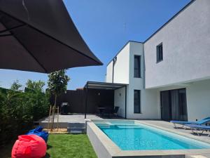 a house with a swimming pool and an umbrella at Villa Cadaques, private pool with heating and salt water in Lozenets