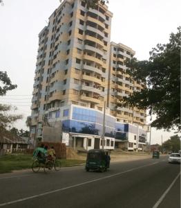 Eine Person, die vor einem hohen Gebäude Fahrrad fährt. in der Unterkunft Sylhet, Hill View Tower, Shah Poran,Khadim para, Sylhet in Sylhet + 11 Fotos