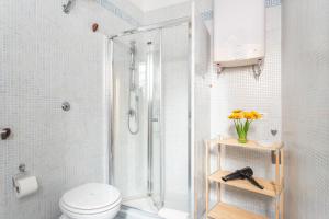 a bathroom with a shower with a toilet and a vase of flowers at Black & White in Cagliari +61 photos