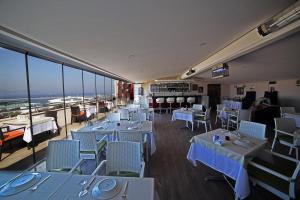 a restaurant with white tables and chairs and windows at Hotel Villa Marina in Bandırma