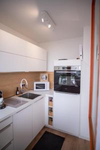 a white kitchen with a sink and a microwave at Cozy apartment with pool I U-Bahn in Munich +8 photos