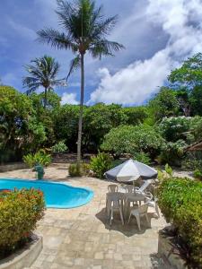 a patio with a table and an umbrella next to a pool at Casa charme pipa in Pipa