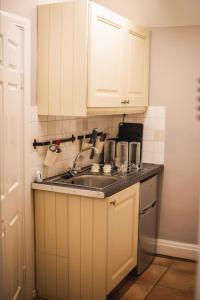 a kitchen with white cabinets and a sink at Dykeneuk rooms in Hartburn