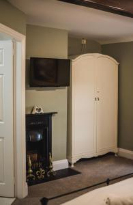 a room with a tv and a cabinet and a fireplace at Dykeneuk rooms in Hartburn