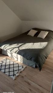 a bed sitting on top of a wooden floor at Maison de 50m2 à la campagne in Pirmil