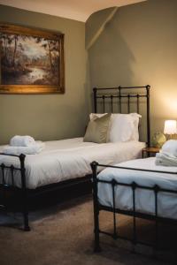 two beds in a room with a painting on the wall at Dykeneuk rooms in Hartburn