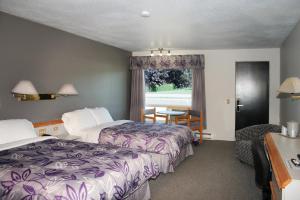 a hotel room with two beds and a table and a window at Motel à la Brunante Petit Déjeuner inclus avec la chambre in Sainte-Anne-des-Monts +9 photos