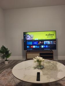 a living room with a tv and a table with flowers at Peace Home in Dieppe +2 photos