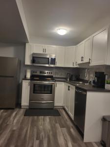 a kitchen with stainless steel appliances and white cabinets at Peace Home in Dieppe