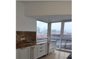 a kitchen with white cabinets and a large window at Hotel Sir Orhideea in Bucharest