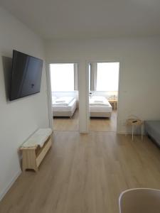 a white room with two beds and a flat screen tv at Apartmány ALMA Šumiac in Šumiac