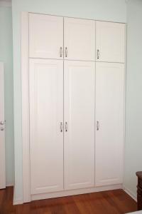 a row of white cabinets in a room at Apartman A4 - Dvorac Belimarkovic in Vrnjačka Banja +9 photos