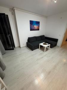 a living room with a black couch and a table at Apartment Pitesti in Piteşti