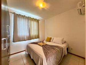 a small bedroom with a bed with a window at Apto em Barra Velha 340m da PRAIA com SACADA com CHURRASQUEIRA, AR CONDICIONADO WI-FI, PISCINA, PORTARIA 24h, ACADEMIA MINI MERCADO e vaga de GARAGEM in Barra Velha