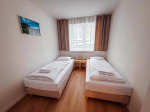 two beds in a room with a window at Apartmány ALMA Šumiac in Šumiac