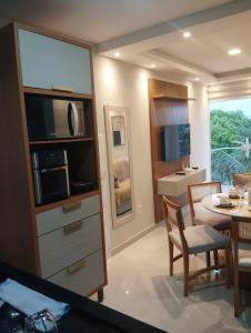 a kitchen and dining room with a table and a microwave at 05 minutos da praia - Casa Superior céu azul Buzios in Búzios