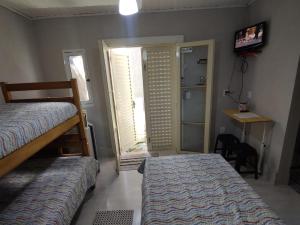 a bedroom with two beds and a door with a television at Quarto Paulínia 2 in Paulínia