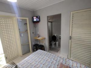 a bedroom with a bed and a tv on the wall at Quarto Paulínia 2 in Paulínia