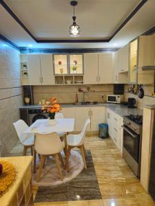 a kitchen with white cabinets and a table and chairs at Joli F3 in Dar el Beïda