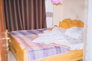 a wooden bed with a blue and white comforter at Davidson's guest house in Kayonza