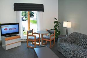 a living room with a tv and a table and chairs at Motel à la Brunante in Sainte-Anne-des-Monts