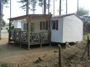a small white tiny house with a porch at ZEcamping 4 étoiles animaux acceptés avec piscine chauffée toboggan et tennis in Ucel