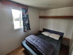 a small bedroom with a bed with a window at ZEcamping 4 étoiles animaux acceptés avec piscine chauffée toboggan et tennis in Ucel