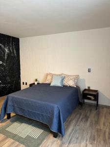 a bedroom with a bed with a blue comforter at Deluxe Loft Air Conditioning Downtown Parking in Tepatitlán de Morelos