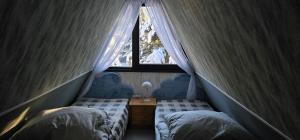 two beds in a room with a window at A-Frame am Ochsenkopf in Mehlmeisel