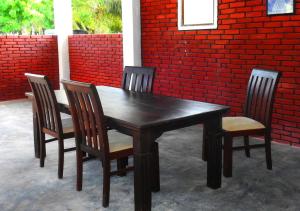 a wooden table and four chairs in front of a brick wall at Coral Waves Inn - Pasikuda in Kalkudah