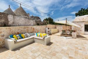 a patio with a couch with colorful pillows on it at Trulli Dafani in Ostuni