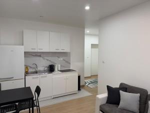 a kitchen with white cabinets and a living room at L'Appart Chaleur in Oyonnax