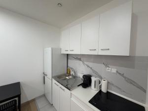 a white kitchen with a sink and a refrigerator at L'Appart Chaleur in Oyonnax +7 photos