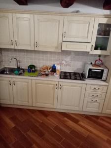 a kitchen with white cabinets and a sink and a microwave at Al Nido Del Passero 1 in Greccio