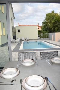 a table with plates on it next to a swimming pool at Villa Majra in Valbandon
