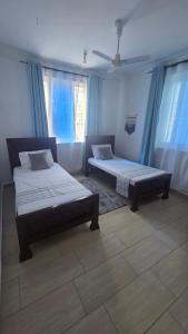 two beds in a room with blue curtains at Seasalt & Sand in Mtwapa +28 photos