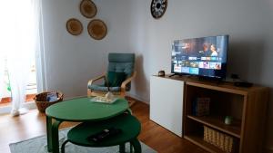 a living room with a green table and a television at BENAMAR HOUSE in Quarteira